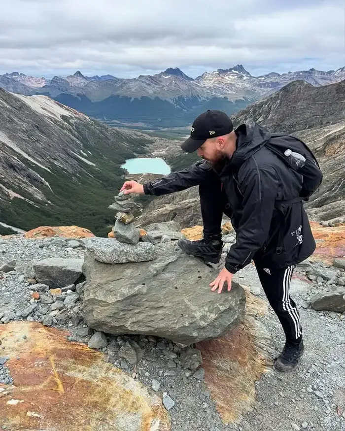 Felipe Veloso empilhando pedras em cima de uma montanha.